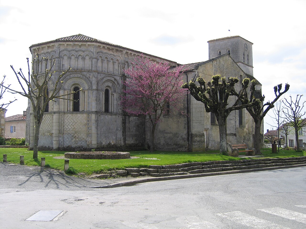 Église romane Notre-Dame de Rioux vue depuis les jardins, avec son clocher carré du XVe siècle et son abside sculptée, Charente-Maritime