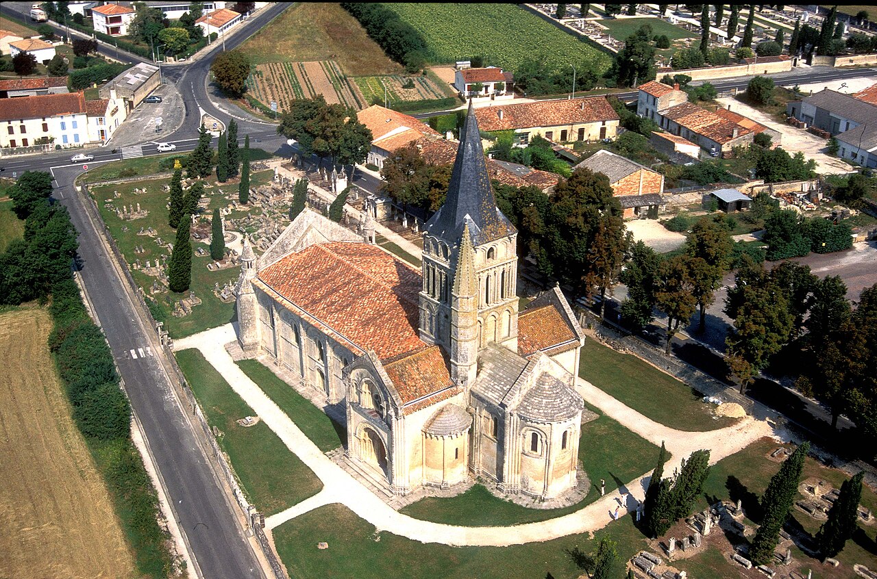 Vue aérienne de l'église Saint-Pierre d'Aulnay montrant le plan en croix latine et le cimetière, Charente-Maritime